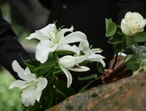 Saiba como é e como fazer um enterro ecológico! Familiares se despedindo do ente querido com flores, no enterro ecológico.
