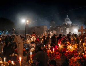 Conheça culturas de celebram a morte! Multidão celebra o Dia dos Mortos em cemitério iluminado por velas em culturas que celebram a morte.