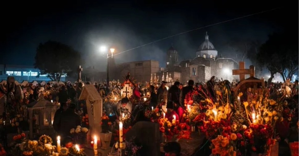 Multidão celebra o Dia dos Mortos em cemitério iluminado por velas em culturas que celebram a morte.